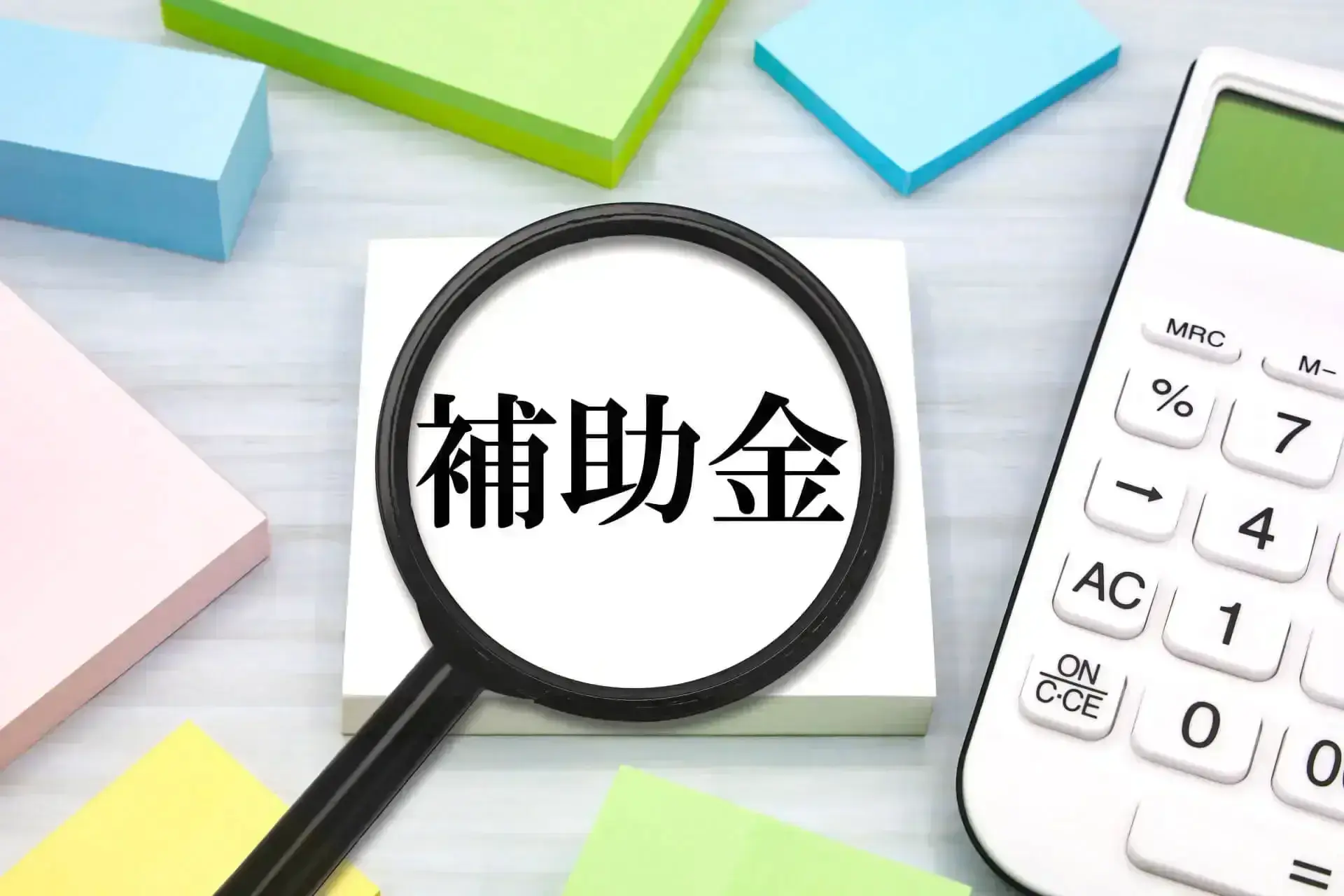 電卓と補助金を示す虫眼鏡
