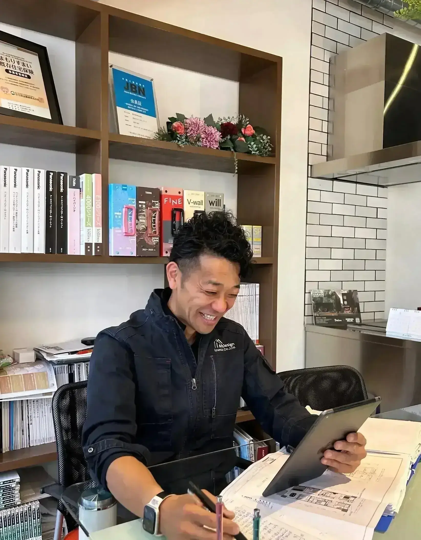 図面とタブレットを確認する現場監督